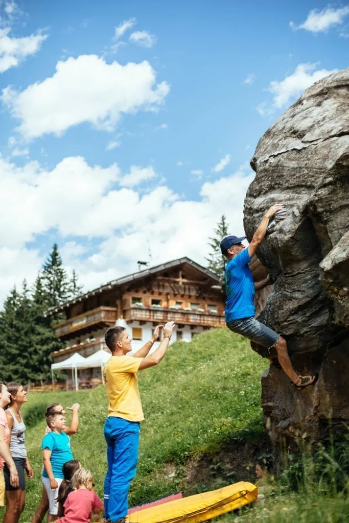 Familie beim Bouldern am Fels vor dem Hof