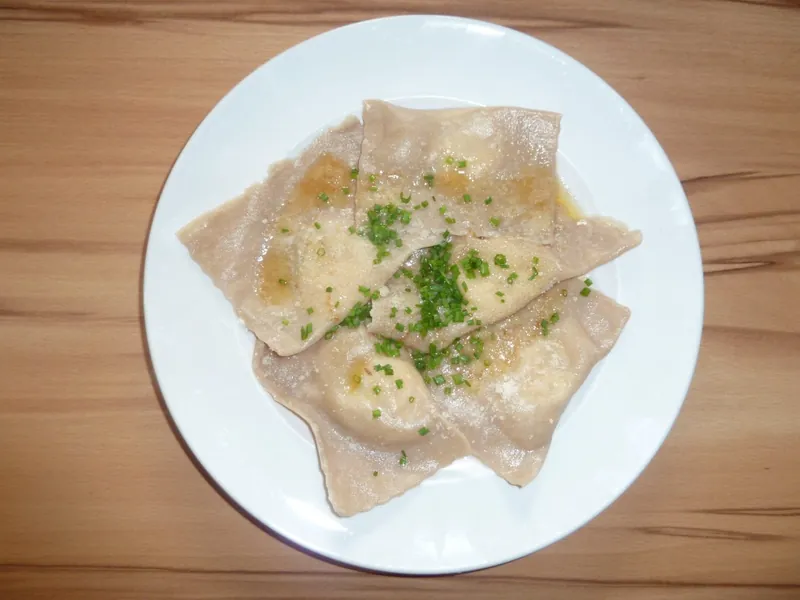 Schlutzkrapfen mit Schnittlauch auf weißem Teller