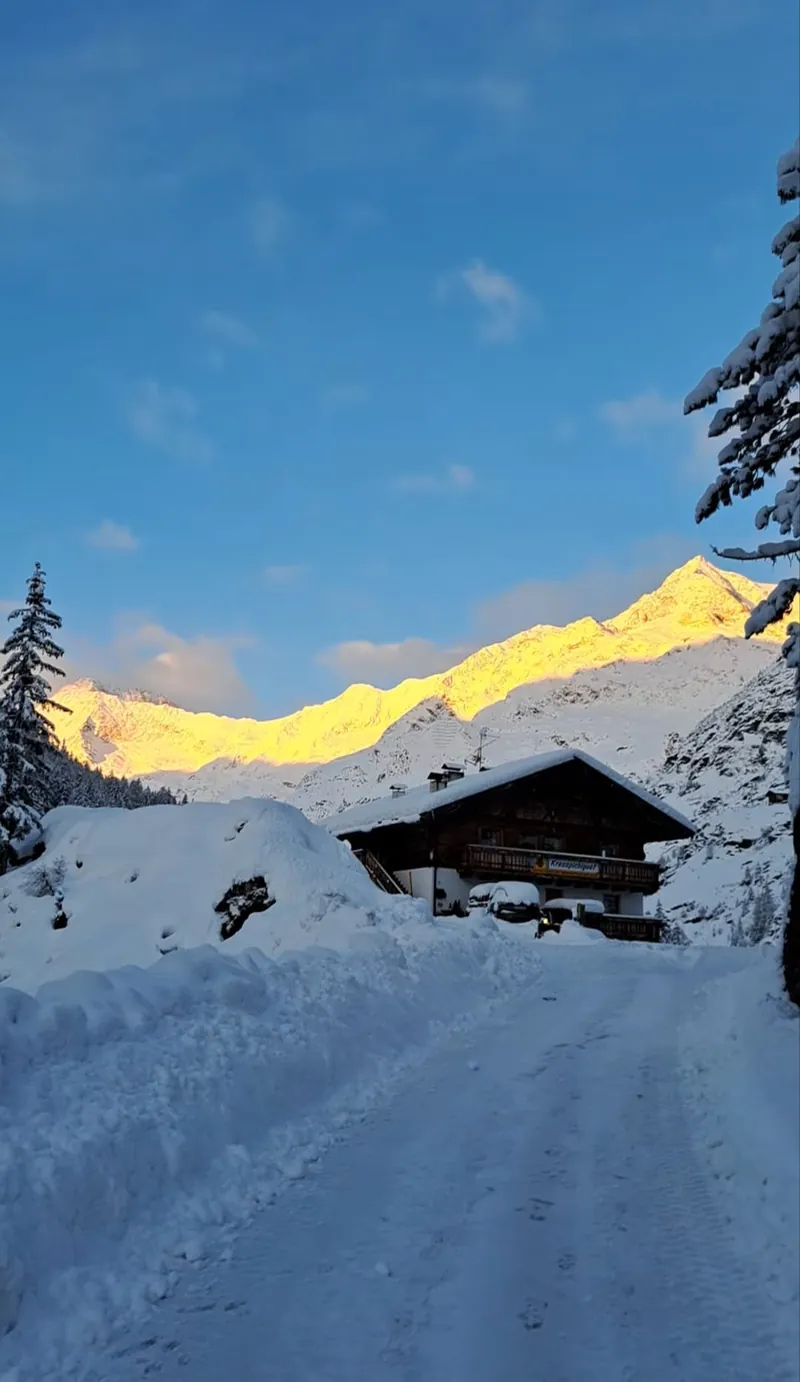 Der Kresspichlguet im Schnee, die Gipfel dahinter im Alpenglühen
