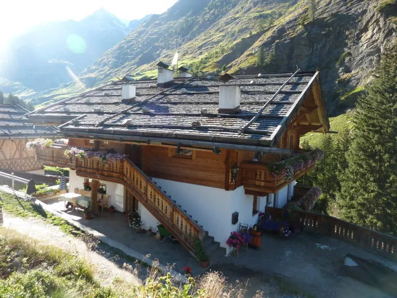 Das Bauernhaus Kresspichlguet im Sommer mit Balkonen und Bergen dahinter