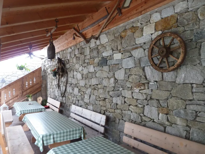 Die Terrasse der Hofschenke mit Natursteinwand und Holzbänken